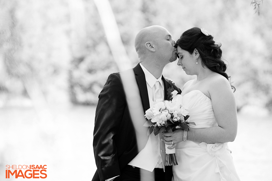 Groom is kissing his bride on the forehead.