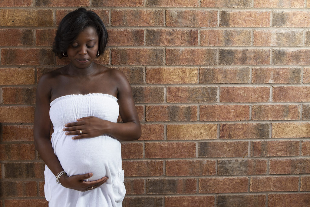 Pregnant woman looks at her baby bump during a maternity photo shoot in Toronto by Ajax Photographer Sheldon Isaac Images