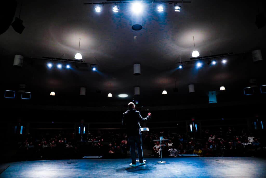 Man speaking to a large crowd in Ajax Church