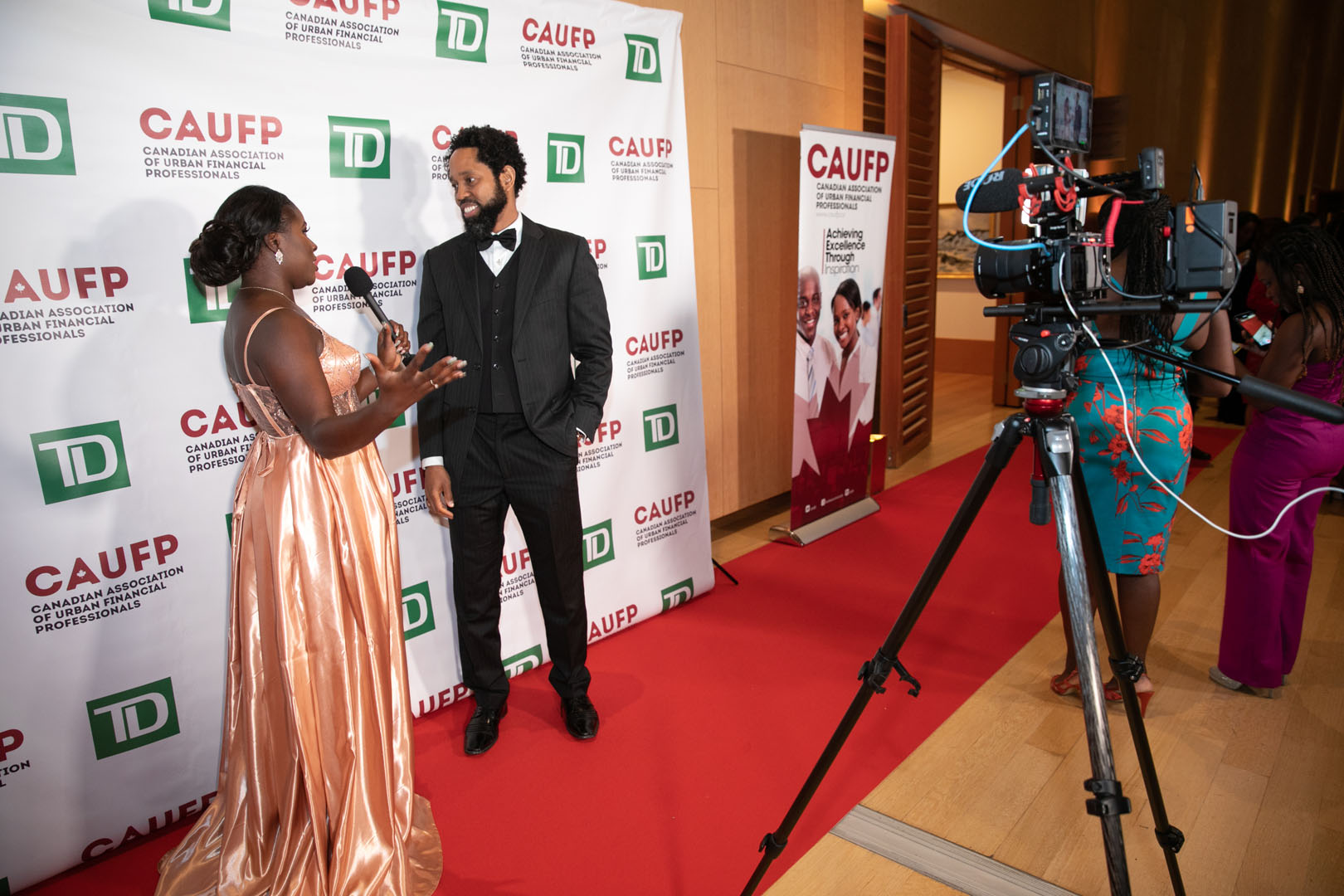 Event Voice Live interview video Toronto — attendee interviewed on the CAUFP gala red carpet, sponsor backdrop in frame