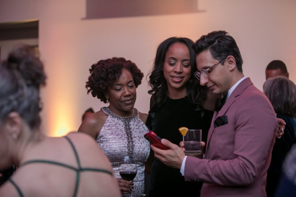 Corporate event photographer Toronto - three guests looking at event photos together on a phone