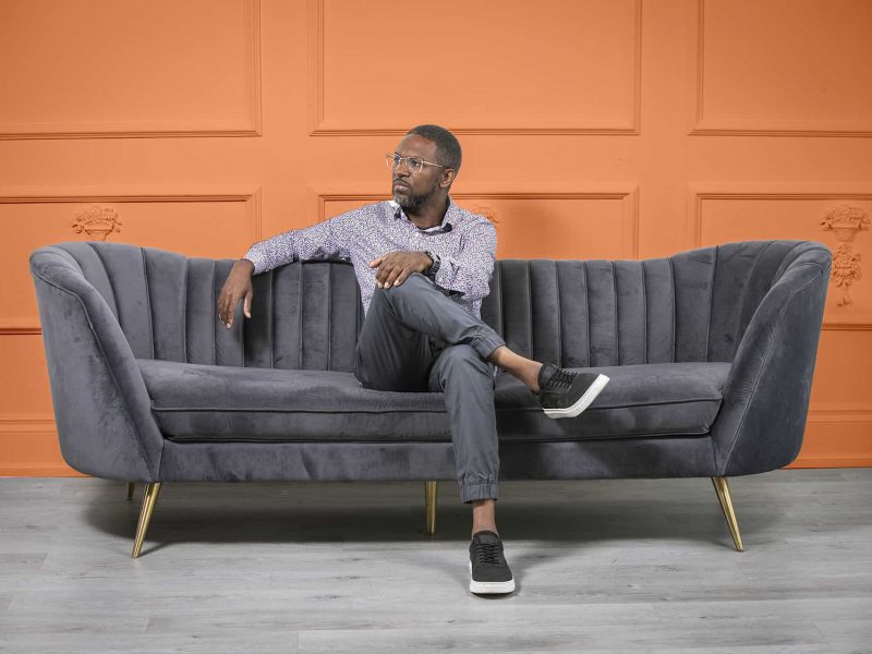 Sheldon sitting on a couch at his photoshoot