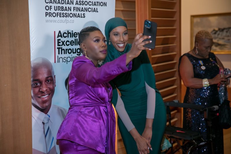 Association event photographer Toronto - two attendees taking a selfie at a branded banner